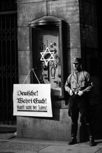 Anti-Semitic boycott Berlin, Germany, April 1, 1933. A Nazi storm trooper stands beside a placard reading, 'Germans, defend yourselves! Do not buy from Jews'. It is posted on the Jewish Tietz store.
